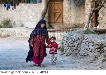 Hunza Valley, Gilgit Baltistan, Pakistan - November 2019: Muslim Woman With Child In Colorful Clothe