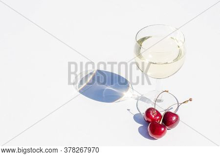 Glass Of White Wine And Some Sweet Cherries On White Background For Concept Trendy Design. Hard Stro