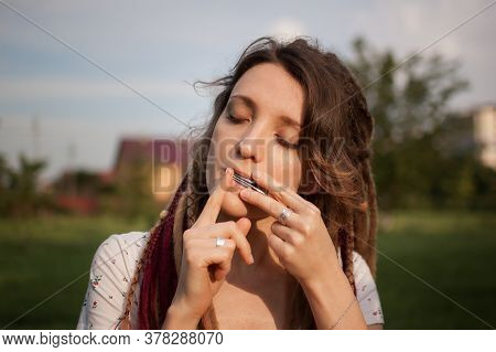 Close-up Outdoors Portrait Of Young Female Shaman With Long Dreadlocks Playing On Traditional Hutsul