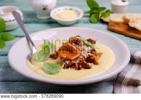 Traditional Polenta With Mushrooms And Cheese In A Dish On A Green Wooden Background. Selective Focu