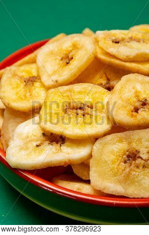 Healthy Sweet Snack, Crispy Dehydrated Unsugared Banana Chips In Bowl On Green Background