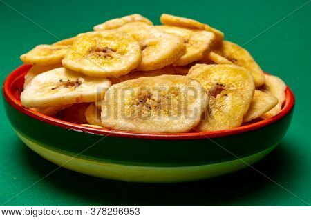 Healthy Sweet Snack, Crispy Dehydrated Unsugared Banana Chips In Bowl On Green Background