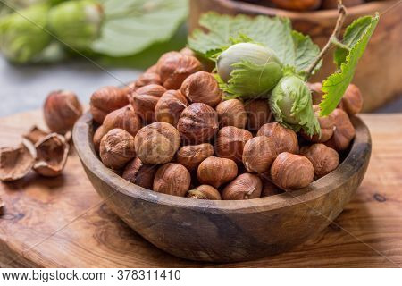Hazelnuts With Peeled Hazelnut And Leaf  In Brown Bowl On Concrete Background. Hazelnuts With Peeled
