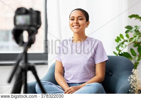 blogging, videoblog and people concept - happy smiling african american female video blogger with camera videoblogging at home