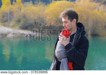 Attractive Young Father With Her Infant Baby In Sling Outdoor. Man Is Carrying Her Child And Travel 