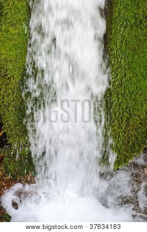Padající voda se zeleným mechem