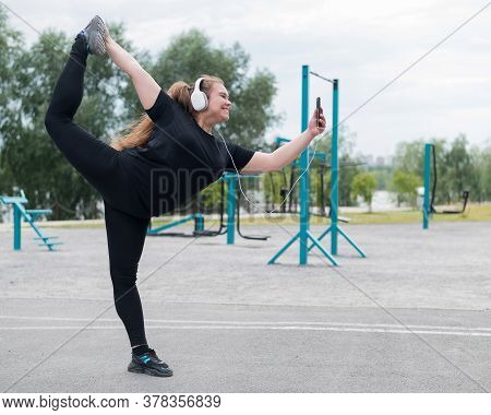 Beautiful Fat Young Woman In Headphones Makes A Figure Skater And Takes A Selfie. A Chubby Smiling G