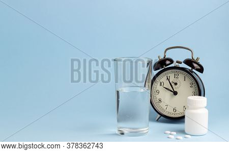 Jar Of Pills, Water And A Clock On A Blue Background. Time To Take Pills. Insomnia.