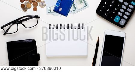 A Wallet, A Credit Card, Money, Glasses, A Blue Pen, A Telephone And A Calculator Lie On A Light Off