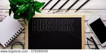 On A Light Table Lie Black Pencils, A Black Drawing Board, A Telephone, An Empty Notebook, There Is 