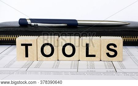 A Word Tools Written In A Wooden Cube With A Pen And Wallet