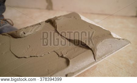 The Master Smears The Tiles With Glue. The Master Tile Smears The Mucilage Solution On The Marble Ti