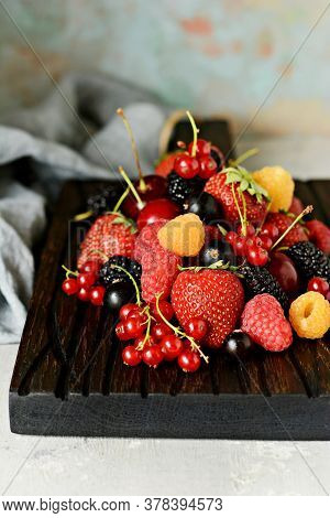 Summer Berries On A Wooden Board Close-up. Berry Fruits Like Strawberries, Blueberries, Red Currants