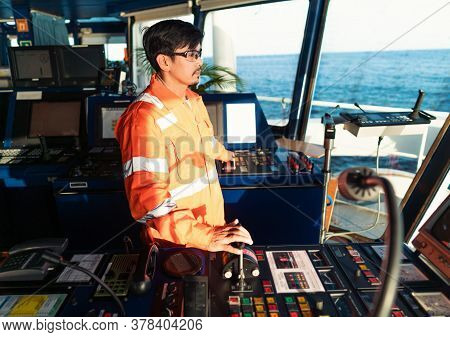 Filipino Deck Officer On Bridge Of Vessel Or Ship. He Is Speaking On Gmdss Vhf Radio