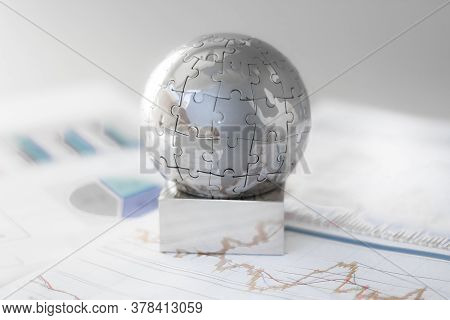 Metal Globe Resting On Paper Currency. Spherical Puzzle With A Single Piece Disconnected