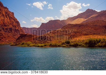 Historic boat crossing Lee's Ferry. Smooth turn of the magnificent Colorado River. Amazing wildlife. Steep river banks of red sandstone. USA. The concept of active, extreme and photo tourism