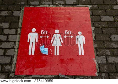 A Crumpled Protective Mask Lies On A Red Sign That Informs People To Keep A Social Distance. Sign In
