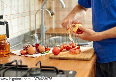 A Man Cuts A Peel With A Knife From A Red Apple. Food Waste And Offcuts While Preparing Food On The 