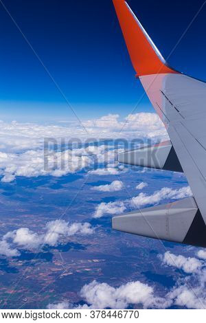 Aerial View Of Cloud Blue Sky And Plane Wing View Through The Airplane Window