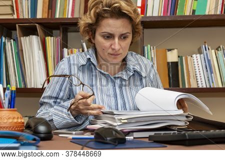 Image Of A Busy Woman Teleworking At Her Desk At The Home. Working At Home Became An Important Recom