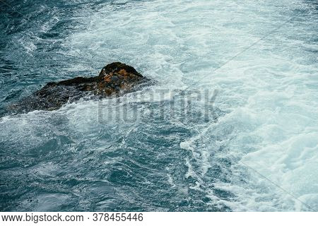 Mossy Stone In Azure Water Of Mountain River Close-up. Blue Nature Background With Boulder With Moss