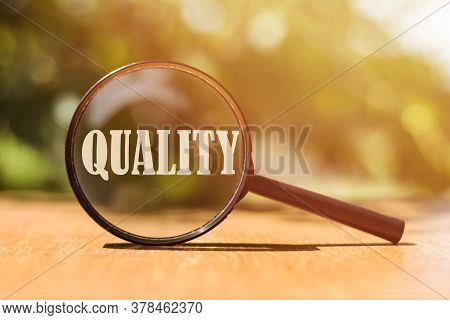 Magnifier Glss With Text Quality On Wooden Table In Sunlight. Business Concept