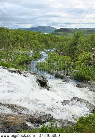 Streamlet Waterfall From Lake Tsahkal In Northern Lapland Wilderness, Fells On The Background