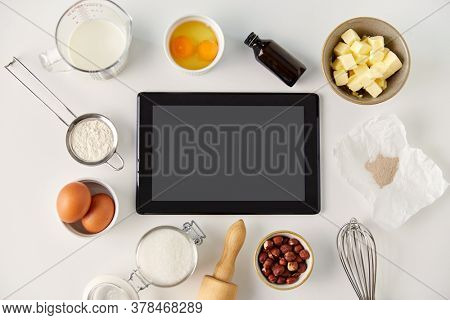 food, culinary and technology concept - tablet pc computer and cooking ingredients on table