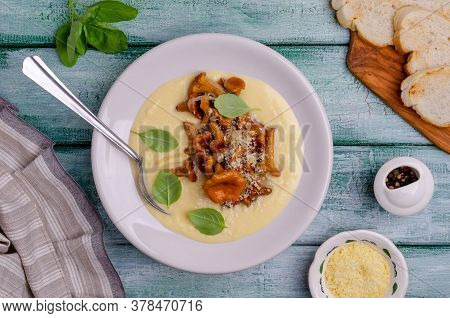 Traditional Polenta With Mushrooms And Cheese In A Dish On A Green Wooden Background. Selective Focu