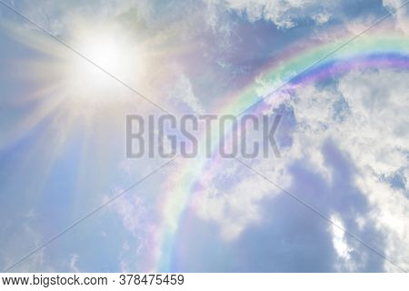 Summer Sun Burst And Blue Sky  Rainbow - Massive Sun Radiating Beside Fluffy Clouds With A Giant Arc