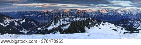Amazing Sunset Alpenglow Panorama View To Snow Covered Mountain Ranges And Dramatic Sky In Cold Wint