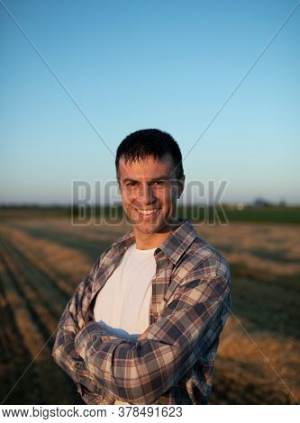 Handsome Farmer With Crossed Arms Standing In Field During Harvest