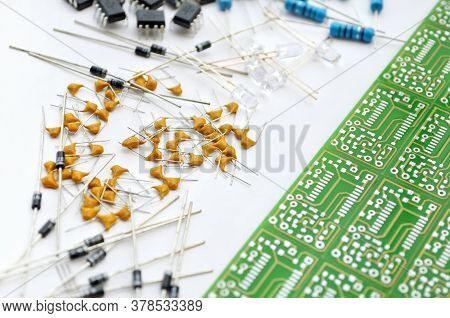 Set Of Various Electronic Components Arranged Near Green Electronic Circuit Board On White Backgroun