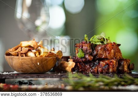 Pork ribs cooked at low temperature. Blackcurrant sauce, parsnip chips with Parmesan cheese. Delicious healthy meat food closeup served on a table for lunch in modern cuisine gourmet restaurant.