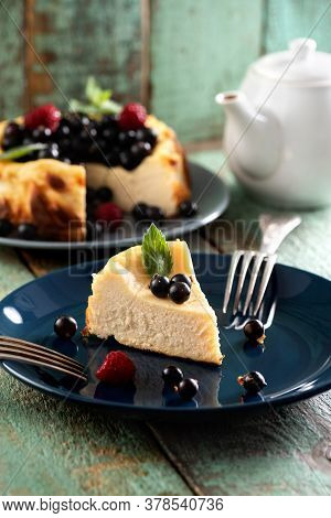 Berry Cheesecake Cut On Deep Blue Plate With Teaware On Old Painted Wood Background