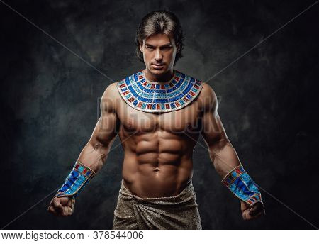 Athletic Man In Ancient Egyptian Costume Posing In The Studio With His Fists Clenched