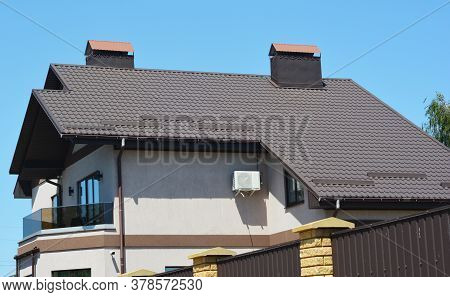 A House With A Saltbox, Catslide Brown Metal Roof With Snow Stoppers, Chimneys And Rain Gutter With 