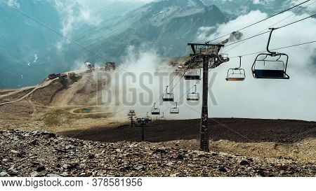 Cableway Near Smoke In Rocky Countryside. Modern Ropeway Located On Stony Ground Near Thick Fume In 