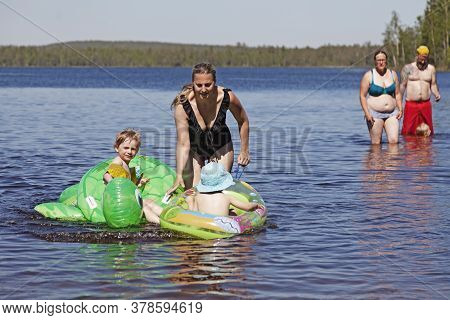 Umea, Norrland Sweden - June 20, 2020: Mother And Child Playing In The Water With Inflatable Animals