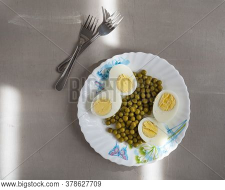 Light Breakfast With Boiled Eggs And Green Peas On A Light Plate, Forks Top View