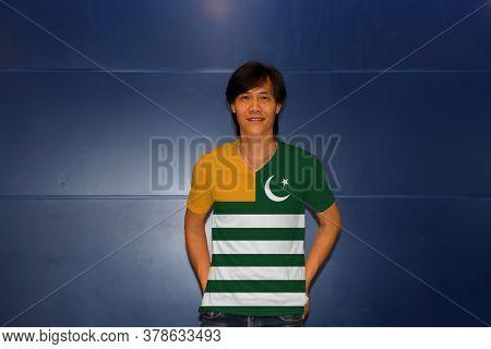 Man Wearing Azad Kashmir Flag On Shirt And Standing On The Blue Wall Background. Green Background Wi