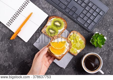 Woman Holding In Hand A Sandwich With Cream Cheese And Orange Healthy Snack At Workplace In Office