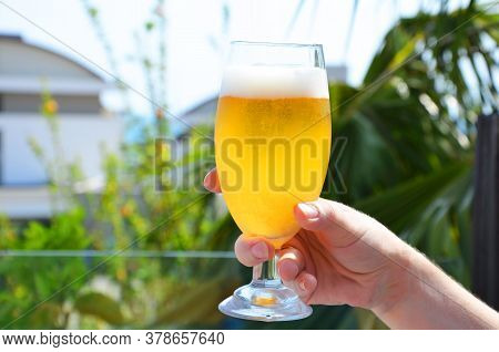 Hand Holding A Glass Of Beer In Beach Tropical Sea Background. Vacation Holiday Concept