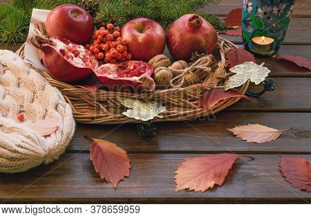 Apples, Pomegranate, Cinnamon, Cones, Walnuts, Fallen Leaves And Burning Candle On A Wooden Backgrou