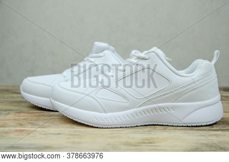 Beautiful Pair Of New White Women's Sneakers On A Wooden Background Close Up