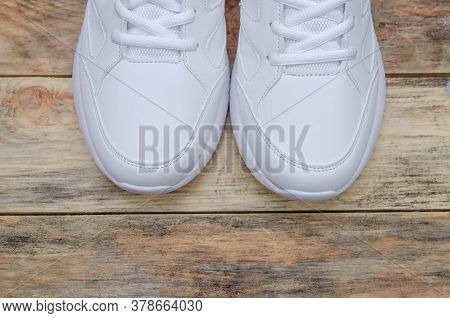 Beautiful Pair Of New White Women's Sneakers On A Wooden Background Close Up, View Top. Sock Part Of