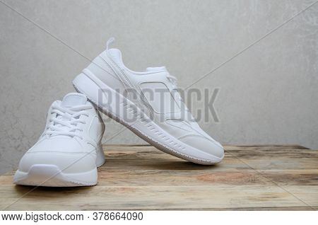 Beautiful Pair Of New White Women's Sneakers On A Wooden Background Close Up