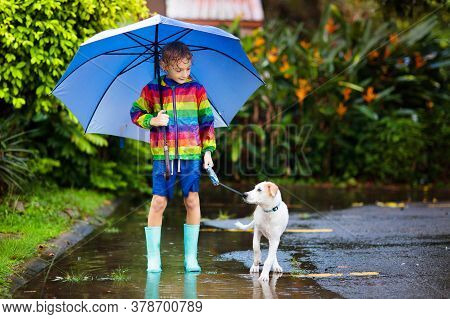 Kids In Puddle In Autumn Rain. Waterproof Wear