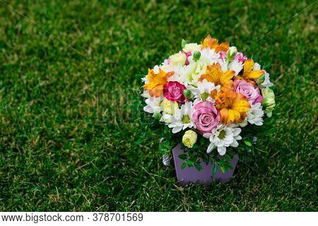 A Bouquet Of Colorful Flowers In A Hatbox On A Green Lawn. Top View. Place For Text.