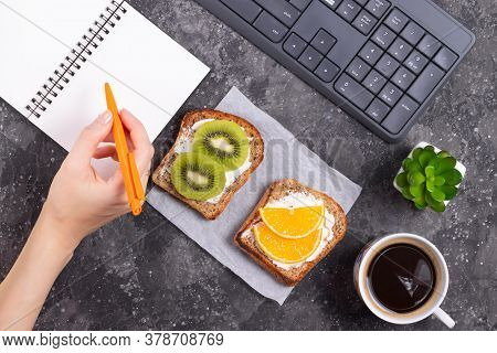 Woman Making Notes In Notebook At Lunch With Fruit Sandwiches And Keyboard